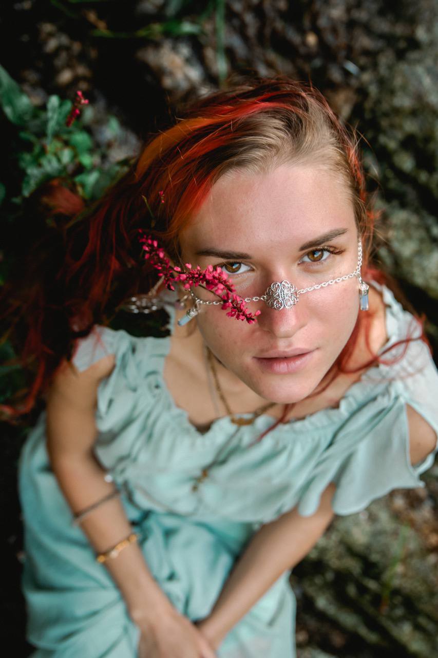 High-angle portrait of woman with red hair wearing silver floral facechain with flowers